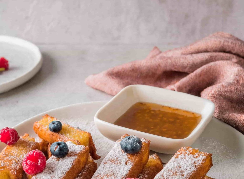 Crispy and Irresistible Frozen French Toast Sticks in Air Fryer 15 A plate of crispy air-fried French toast sticks served with maple syrup and fresh berries.